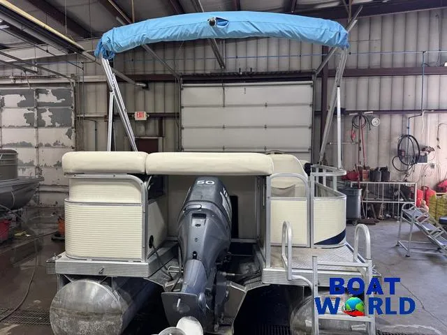 Slide: The Image of 2005 Bennington 186L Pontoon boat in a garage with blue canopy and outboard motor. - 37