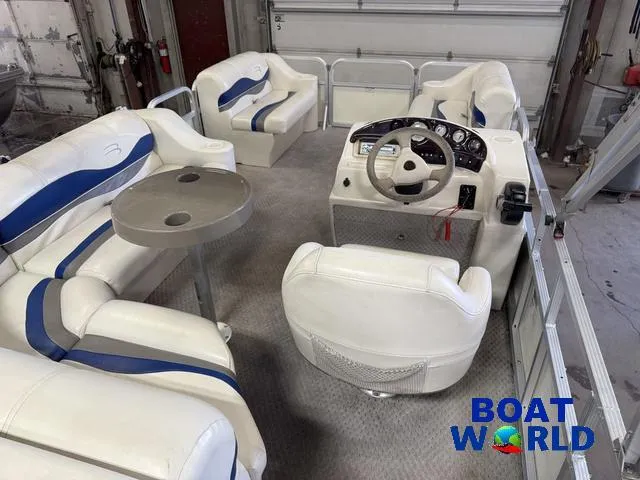 Slide: The Image of 2005 Bennington 186L Pontoon interior with white and blue seating, steering console, and table. - 9