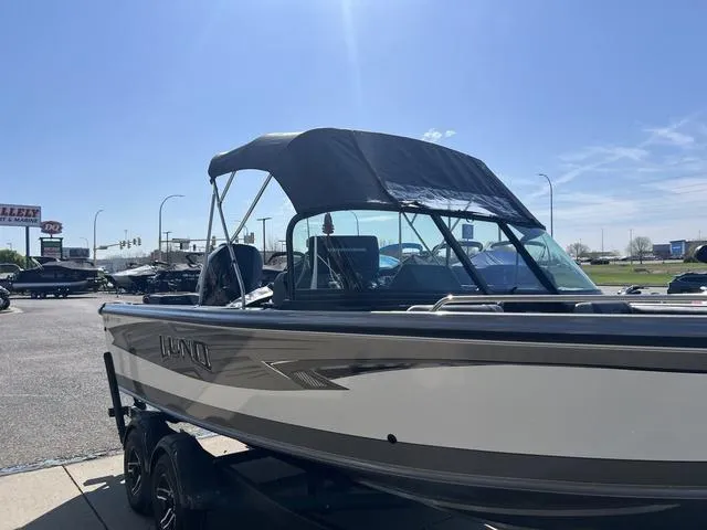 Slide: The Image of 2023 Lund 1975 Tyee Sport boat with canopy, parked outdoors on a sunny day. - 11
