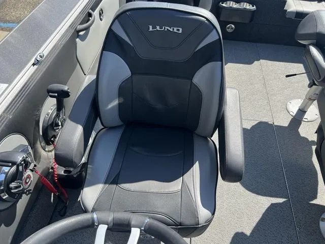 Slide: The Image of Captain's seat in 2023 Lund 1975 Tyee Sport boat, featuring sleek design and controls. - 18