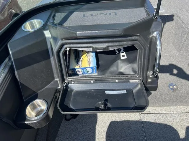 Slide: The Image of Storage compartment in a 2023 Lund 1975 Tyee Sport boat, featuring cup holders. - 28