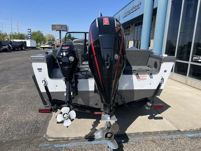 Slide: The Image of 2023 Lund 1975 Tyee Sport boat with dual outboard motors, parked outside a dealership. - 9