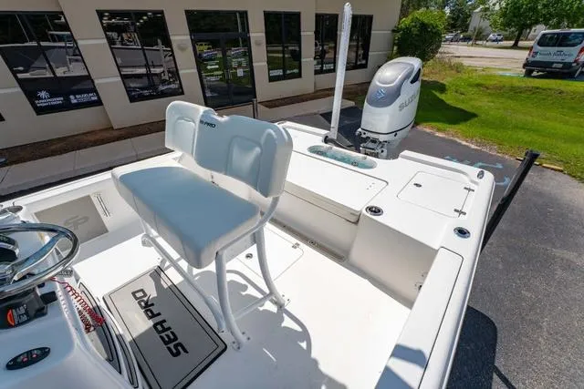 Slide: The Image of 2025 Sea Pro 250 Bay boat with seating and outboard motor, parked near a building. - 10