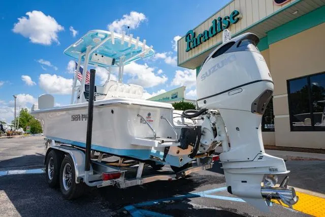 Slide: The Image of 2025 Sea Pro 250 Bay boat on trailer, parked outside a store under a blue sky. - 3