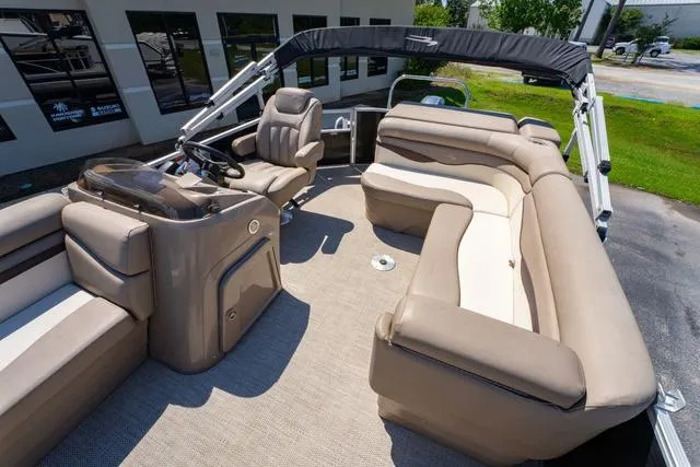 Slide: The Image of 2019 Bennington 20 SX pontoon boat with beige seating and helm, parked outdoors. - 12