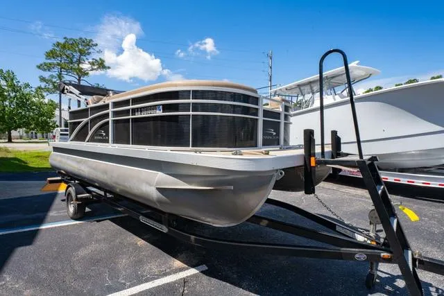 Slide: The Image of 2019 Bennington 20 SX pontoon boat on trailer, parked outdoors under blue sky. - 7