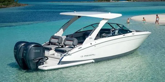 Slide: The Image of 2025 Regal LX9 boat in clear turquoise water near a sandy beach. - 1