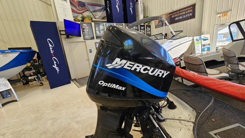Slide: The Image of Outboard motor display featuring Mercury OptiMax engine in a showroom with boats and promotional banners. - 17