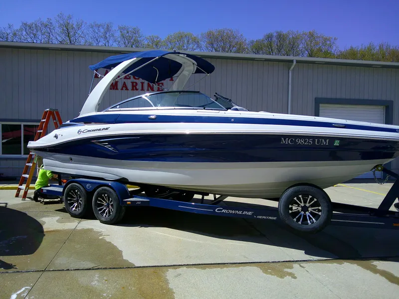 Slide: The Image of 2021 Crownline 255 SS boat on trailer, parked outside a marine facility. - 2