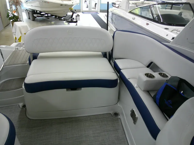 Slide: The Image of 2021 Crownline 255 SS boat interior with white and blue seating, cup holders, and carpeted flooring. - 6