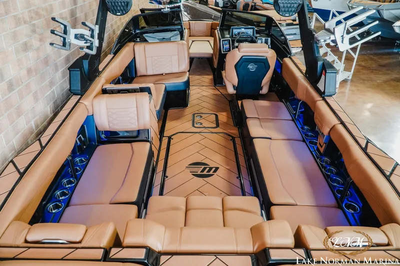Slide: The Image of 2023 Malibu 26 LSV boat interior with tan seating and modern dashboard at Lake Norman Marina. - 12