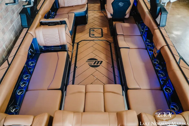 Slide: The Image of 2023 Malibu 26 LSV boat interior with tan seating and blue LED lighting. - 14