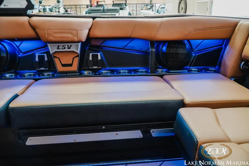 Slide: The Image of 2023 Malibu 26 LSV boat interior with tan seating and blue LED lighting. - 18