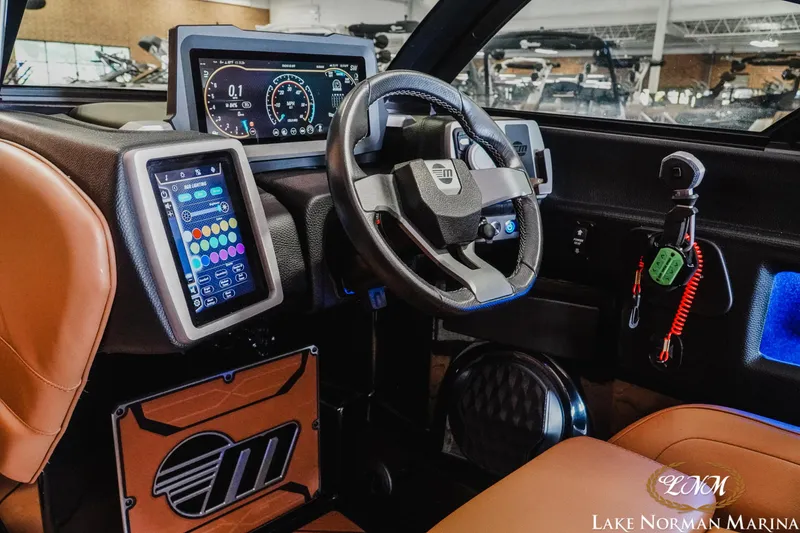 Slide: The Image of 2023 Malibu 26 LSV boat dashboard with advanced digital controls and steering wheel. - 23