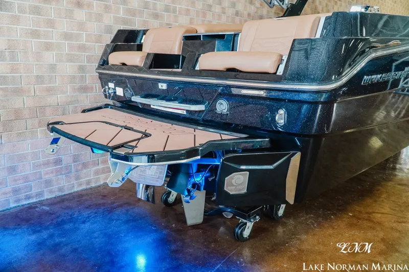 Slide: The Image of 2023 Malibu 26 LSV boat rear view with swim platform and blue lighting. - 8