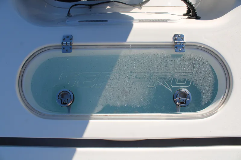 Slide: The Image of 2024 Sea Pro 250 Bay boat livewell with clear lid and dual latches. - 16