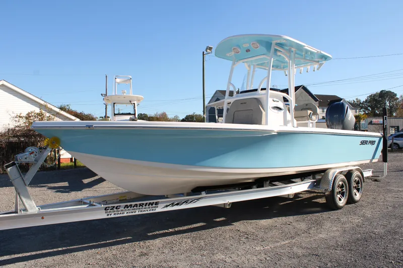 Slide: The Image of 2024 Sea Pro 250 Bay boat on trailer, light blue hull, parked outdoors. - 2