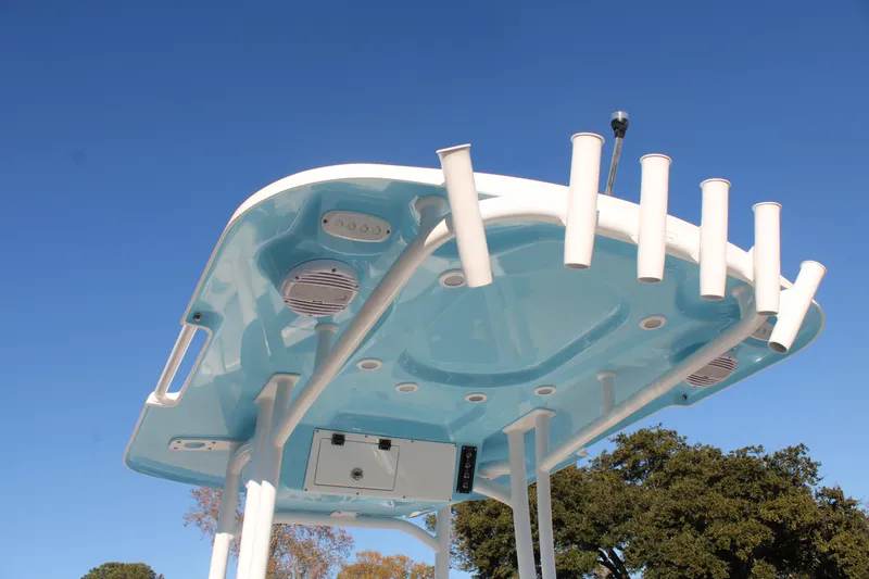 Slide: The Image of 2024 Sea Pro 250 Bay boat top view with rod holders and speakers against blue sky. - 24