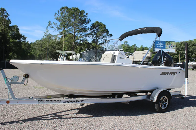 Slide: The Image of 2024 Sea Pro 202 CC boat on trailer, parked outdoors with trees in background. - 4