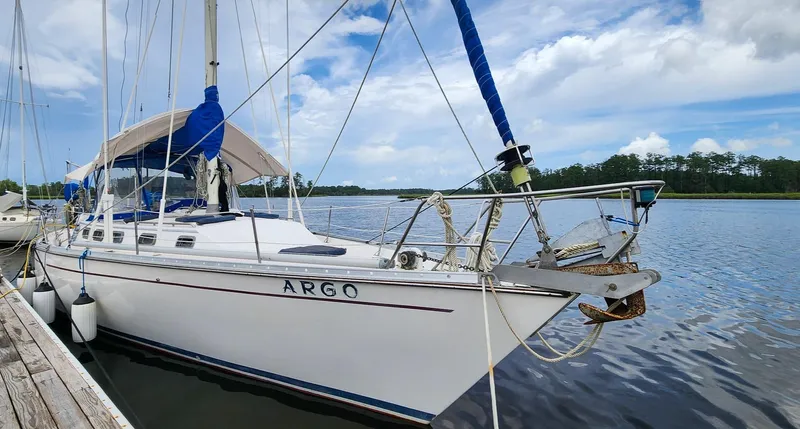 The Image of 1989 Morgan 44 Center Cockpit sailboat docked on a calm lake under a blue sky. - 0