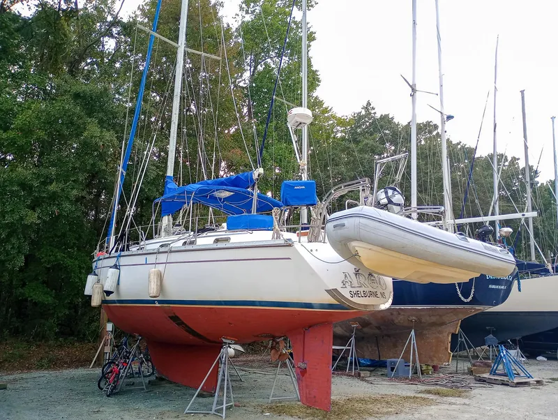 Slide: The Image of 1989 Morgan 44 Center Cockpit sailboat on land, surrounded by trees and other boats. - 26