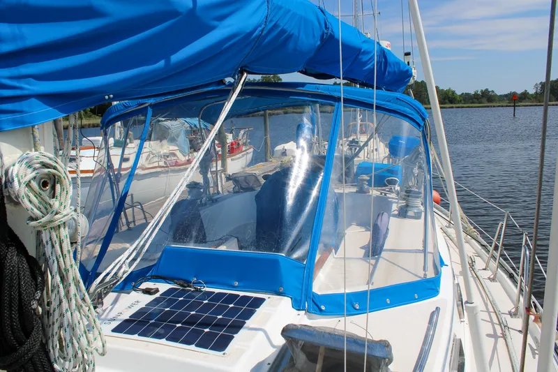 Slide: The Image of 1989 Morgan 44 Center Cockpit sailboat with blue canopy and solar panel, docked by the water. - 36