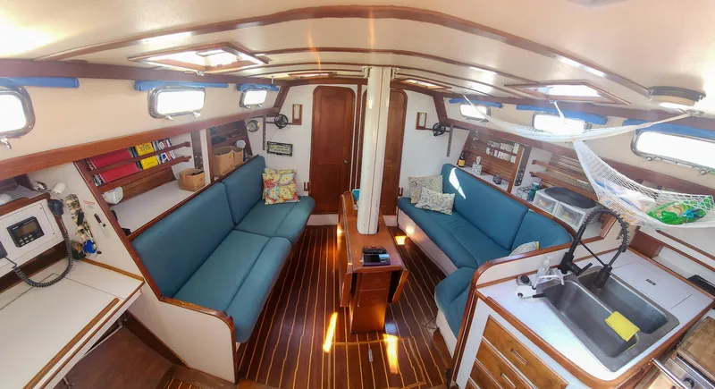 Slide: The Image of 1989 Morgan 44 Center Cockpit interior with blue seating, wood accents, and ample natural light. - 46