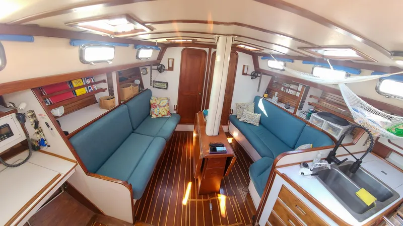 Slide: The Image of Interior of 1989 Morgan 44 Center Cockpit yacht with blue seating and wooden accents. - 47