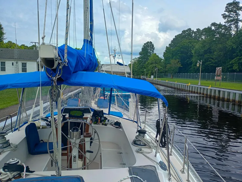 Slide: The Image of 1989 Morgan 44 Center Cockpit sailboat docked in a serene canal setting. - 9