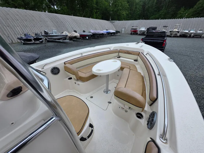 Slide: The Image of 2023 Sea Chaser 22 HFC boat interior with seating and table, parked in a lot. - 8
