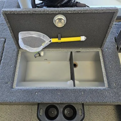 Slide: The Image of 2024 Lund 2075 Tyee boat storage compartment with a yellow-handled net inside. - 11