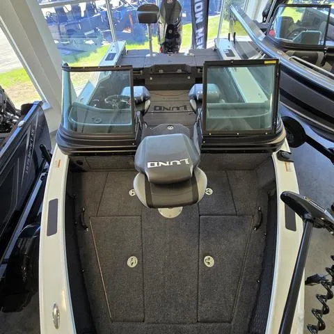 Slide: The Image of 2024 Lund 1875 Pro V Sport boat interior with seating and windshield, displayed indoors. - 5