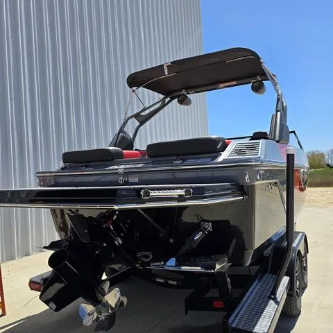 Slide: The Image of 2024 Starcraft MVX IO SURF boat, black exterior, parked outdoors near a building. - 4