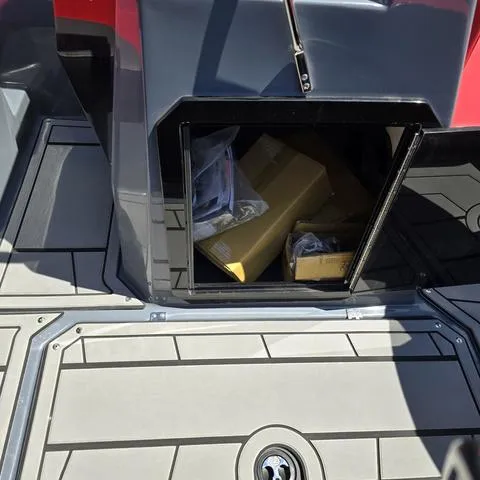 Slide: The Image of 2024 Starcraft MVX IO SURF boat storage compartment with boxes and items inside. - 7