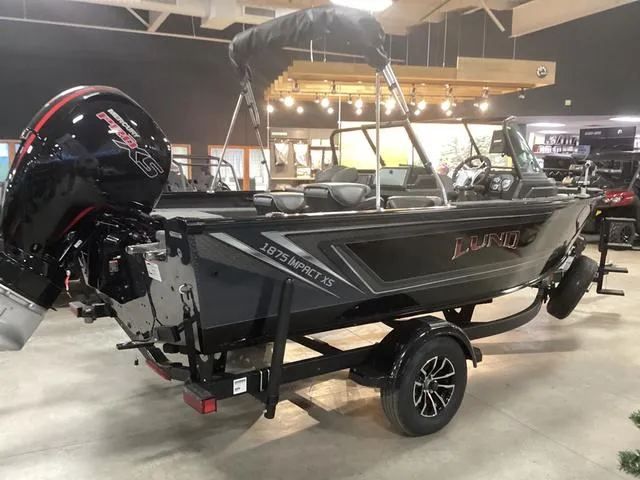 Slide: The Image of 2025 Lund 1875 Impact XS boat displayed indoors on a trailer. - 1