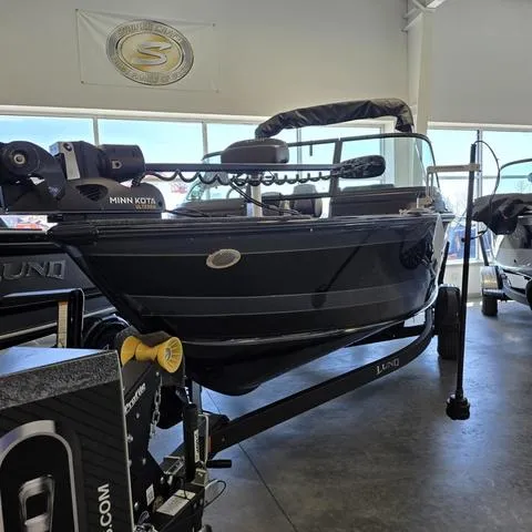 Slide: The Image of 2025 Lund 1875 Impact XS boat displayed indoors with Minn Kota motor. - 4