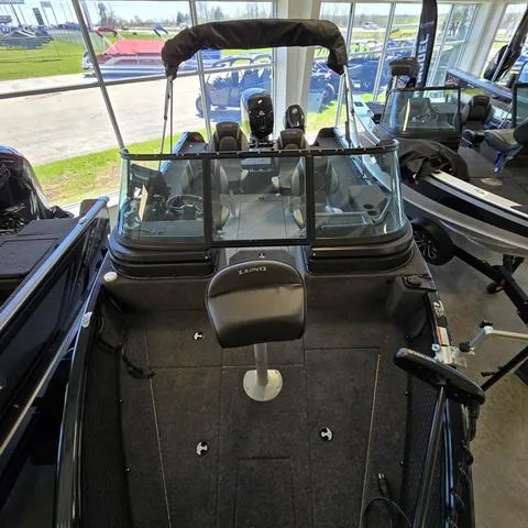 Slide: The Image of 2025 Lund 1875 Impact XS boat interior, featuring seating and steering, displayed in a showroom. - 5
