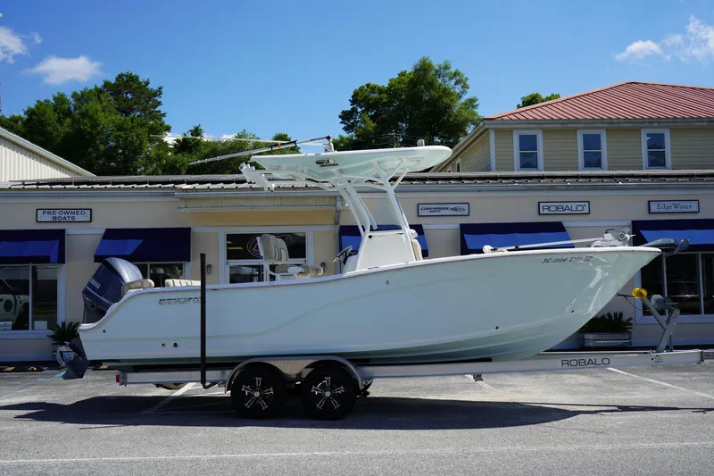 Slide: The Image of 2016 Sea Fox 246 Commander boat on trailer, parked outside dealership under clear blue sky. - 0