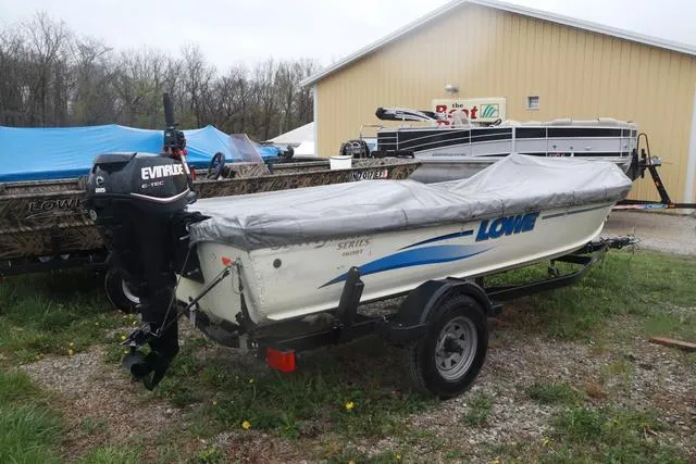 Slide: The Image of 1999 Lowe Sea Nymph 160 BT boat with Evinrude motor, covered and on trailer. - 2