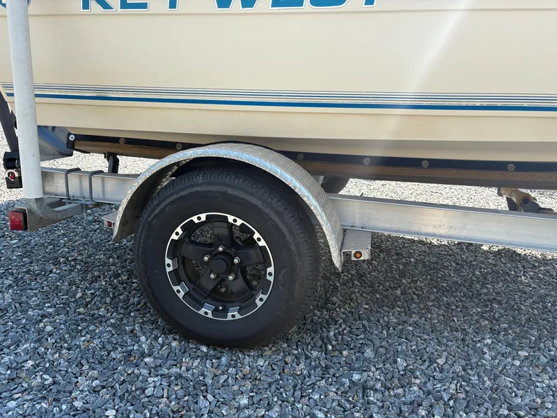 Slide: The Image of 2004 Key West 186 Bay Reef boat on trailer with black wheel, gravel background. - 7