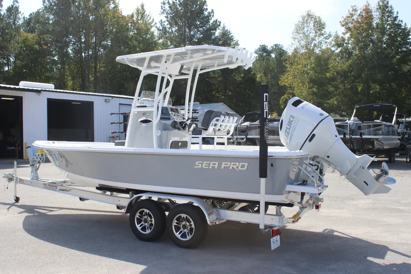 Slide: The Image of 2025 Sea Pro 230 Bay boat on trailer, parked outdoors near trees and a building. - 5