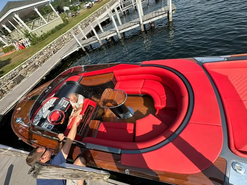 Slide: The Image of 2013 Riva Aquariva 33 with luxurious red seating docked by a lakeside pier. - 12
