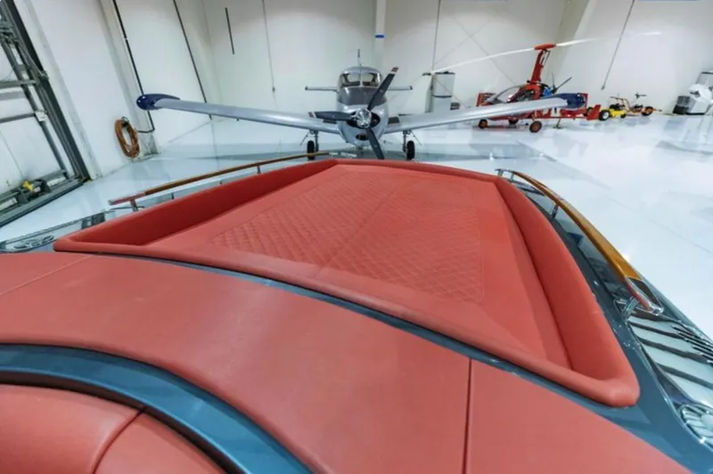 Slide: The Image of 2013 Riva Aquariva 33 with red upholstery in a hangar, small aircraft in background. - 36
