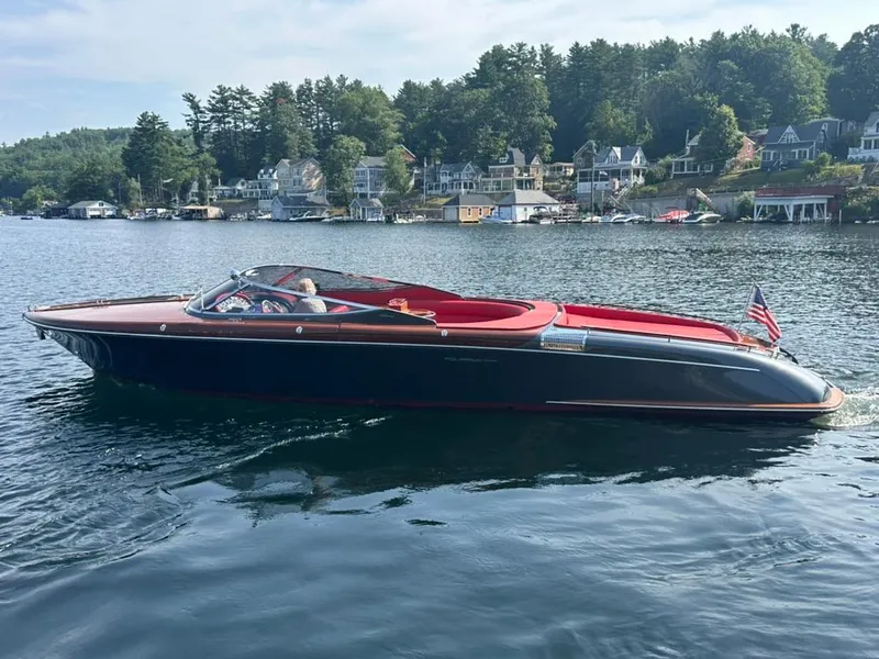 Slide: The Image of 2013 Riva Aquariva 33 boat cruising on a scenic lake with waterfront homes. - 9