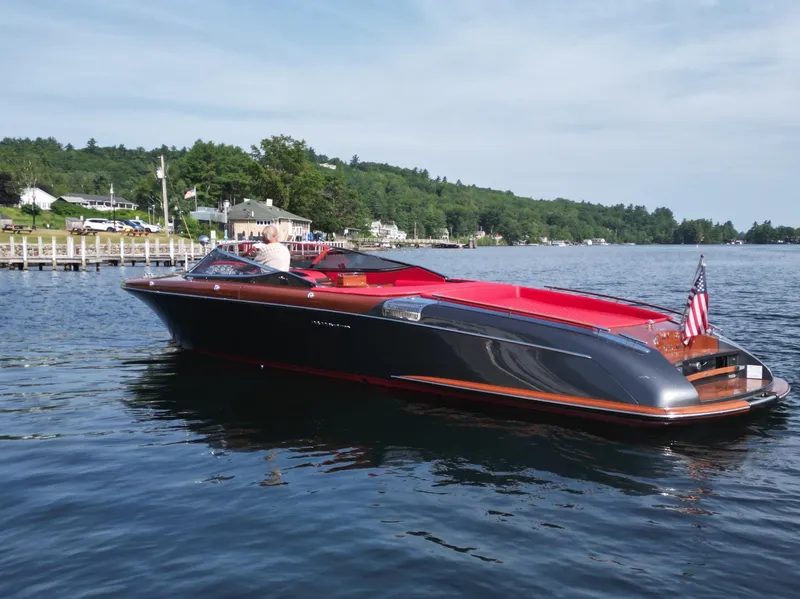 Slide: The Image of 2013 Riva Aquariva 33 luxury boat on a serene lake with scenic background. - 2