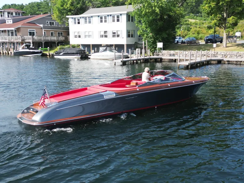 Slide: The Image of 2013 Riva Aquariva 33 boat cruising near a lakeside dock with houses in the background. - 3