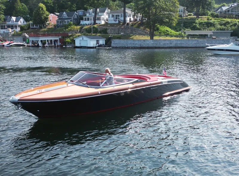 Slide: The Image of 2013 Riva Aquariva 33 luxury boat cruising on a scenic lake with waterfront homes. - 8