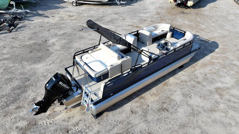 Slide: The Image of 2025 Tahoe Pontoon Sport 85 Versatile Rear Bench on sandy terrain, featuring Suzuki outboard motor. - 11