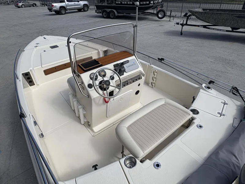 Slide: The Image of 2005 Scout 17 boat interior with steering wheel and seating, parked on concrete. - 4