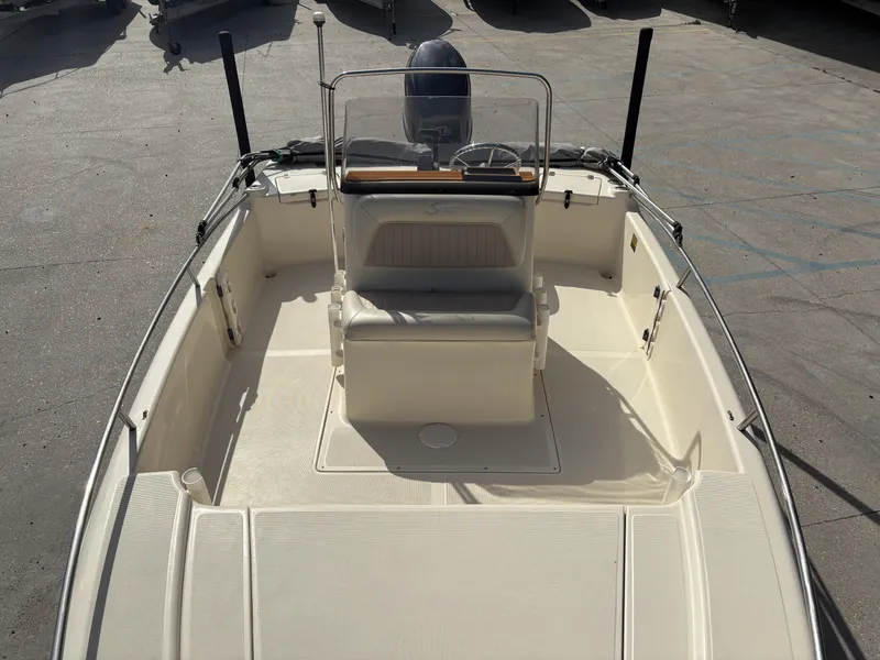 Slide: The Image of 2005 Scout 17 boat interior with seating and steering console, parked on concrete. - 6
